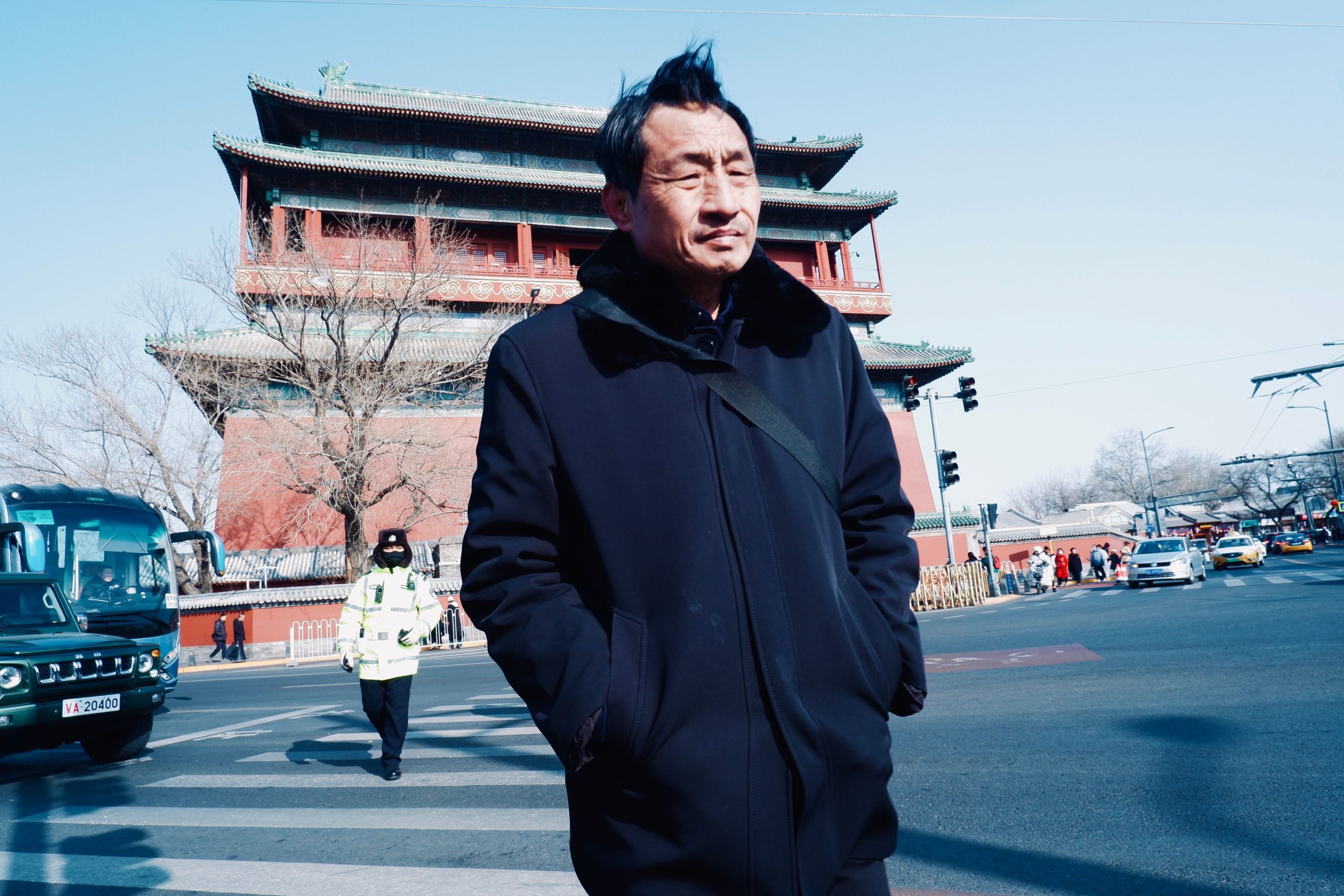 testimonial-skip-02 Man walking near Beijing's historic Bell Tower on a sunny day.