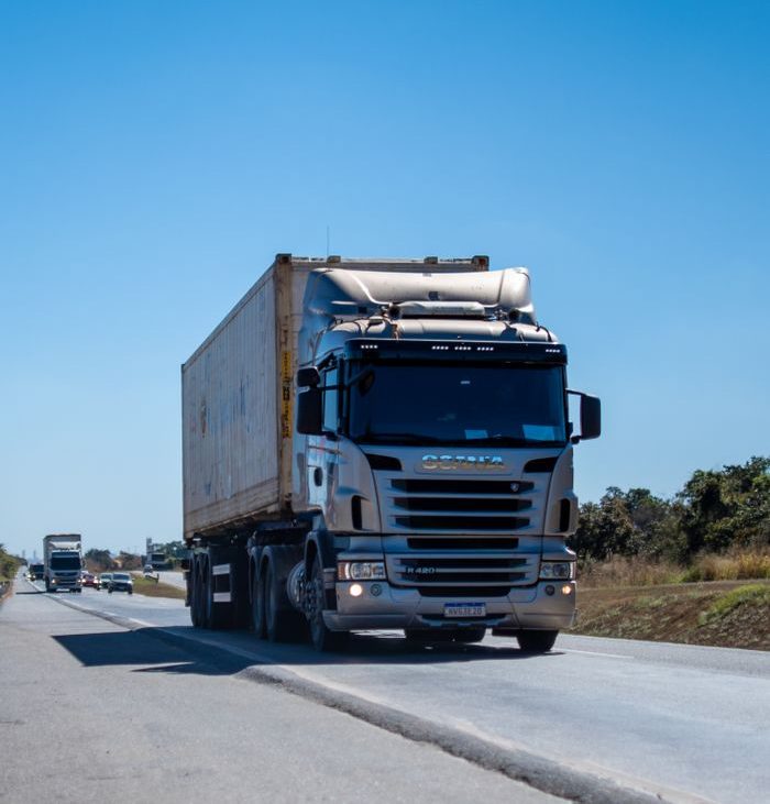 our-services-1 A large cargo truck travels on a highway in Brazil under clear blue skies.